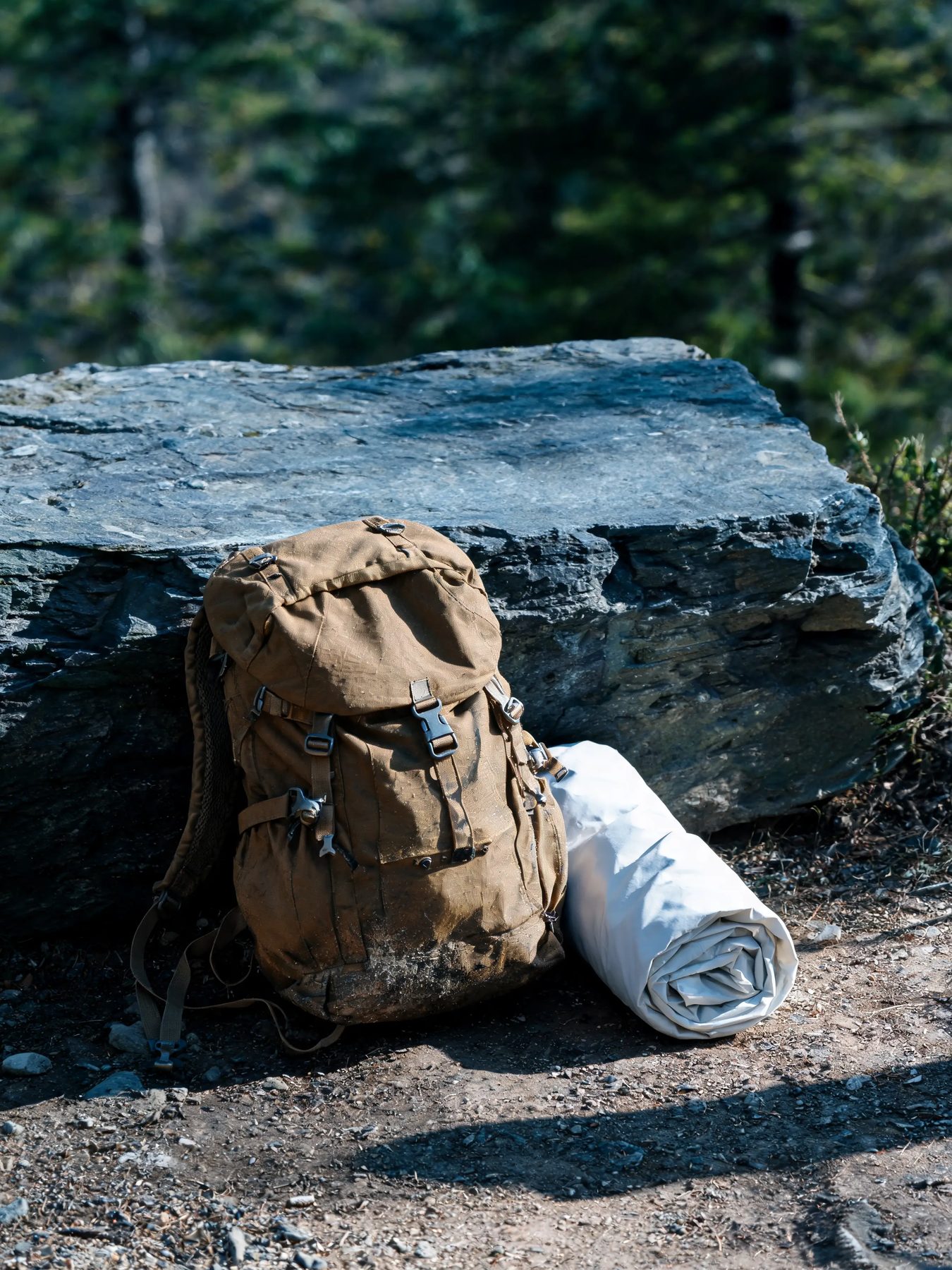 Ripstop daypack and rolled shell jacket against a slate boulder